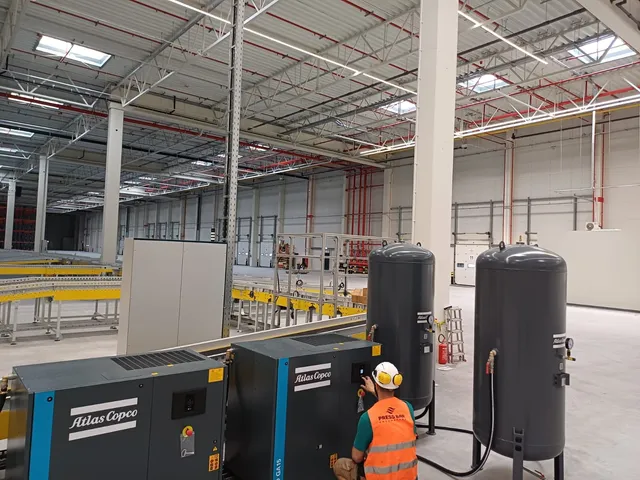 Sprężarki Atlas Copco z pionowymi zbiornikami buforowymi podczas uruchomienia sprężarkowni